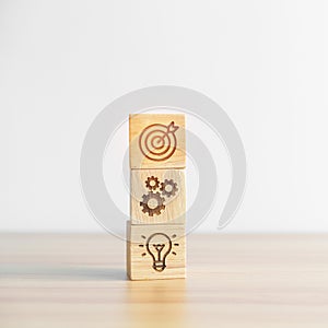 Dartboard above Gear and Lightbulb icon block on desk. business planning process, goal, strategy, target, mission, action,
