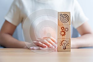 Dartboard above Gear and Lightbulb icon block on desk. business planning process, goal, strategy, target, mission, action,