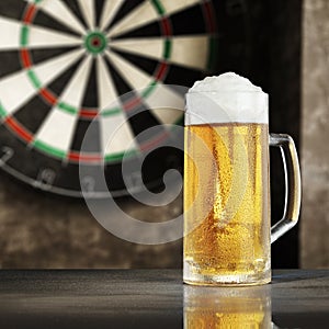 Dartboard with grey wall background. A big glass of cold beer on wooden table with empty space. Darts playing time.