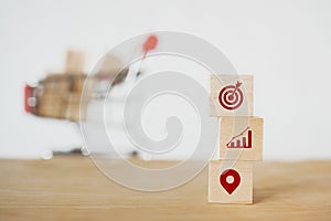 Dartboard, increasing graph and check in icon on stack of wooden cube block with blurred shopping cart for customer target