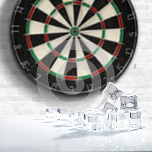 Dartboard with light grey wall background. Ice cubes on white table with empty space. Darts playing time.