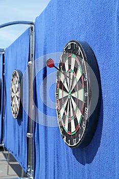 Dartboard with one javelin on blue wall on street