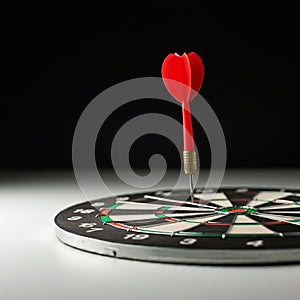 A dartboard with a red dart embedded precisely in the bullseye. The dartboard