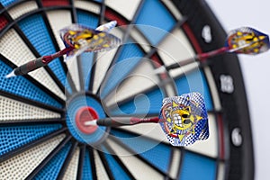 Dartboard with three darts, one hit bullseye with some selective focus