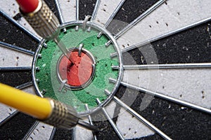 Darts board with a closeup of an arrow hitting the center