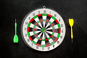 Darts game - simple sport for lesure time. Dartboard and arrows or dart on black background top view