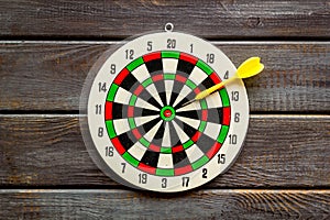 Darts game - simple sport for lesure time. Dartboard and arrows or dart on dark wooden background top view copy space