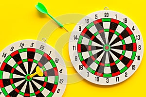 Darts game - simple sport for lesure time. Dartboard and arrows or dart on yellow background top view