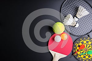 Darts, Racket table tennis, ping pong ball, Shuttlecocks, Badminton racket and Tennis ball on black background.Sport concept, Cop
