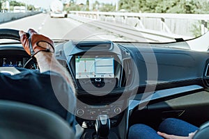 Dashboard View And GPS Map Of Modern Car With Hands Of Driver On Steering Wheel
