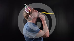 A dashing young man dons a colorful party hat, his bright smile and joyful demeanor capturing the spirit of celebration