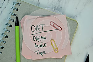 DAT - Digital Audio Tape write on sticky note isolated on Wooden Table