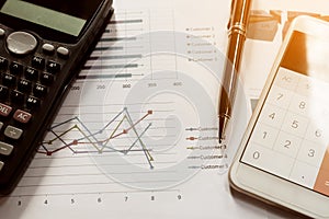 Data analyzing with calculator mobile phone and pen. from charts