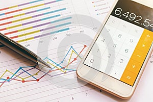 Data analyzing with calculator mobile phone and pen. from charts