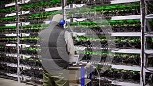 Data center diagnostics technician works and types on laptop. Mining equipment service in server room. Administrator