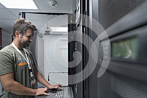 Data Center Engineer Usaing Keyboard on a Supercomputer Server Room Specialist Facility with Male System Administrator