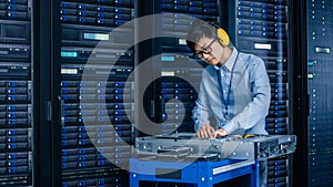 In Data Center: IT Engineer Wearing Protective Muffs Installs New Hardware for Server Rack. Specia