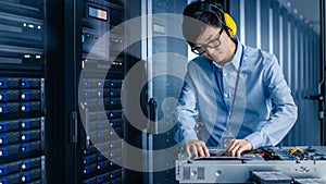 In Data Center: IT Engineer Wearing Protective Muffs Installs New Hardware for Server Rack. Specia
