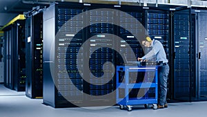 In Data Center: IT Engineer Wearing Protective Muffs Installs New Hardware for Server Rack. Specia