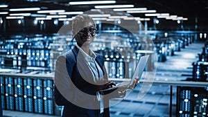 Data Center: Female Programmer Using Laptop Computer, Smiling and Looking at Camera. In Cloud