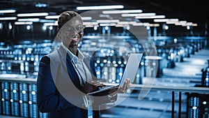 Data Center: Female Programmer Using Laptop Computer, Smiling and Looking at Camera. In Cloud