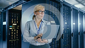 In Data Center: Female IT Technician Running Maintenance Programme on a Laptop, Controls Operation