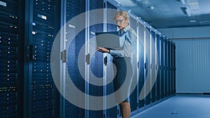 In Data Center: Female IT Technician Running Maintenance Programme on a Laptop, Controls Operation