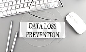 DATA LOSS PREVENTION text on paper with keyboard on grey background