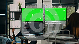 Database developer analyzing greenscreen display on multiple screens