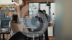 Database programer writing code in front of multiple computer screens displaying artificial intelligence