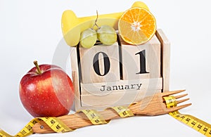 Date of 1 January on cube calendar, fruits, dumbbells and tape measure, new years resolutions