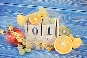 Date 1 January on cube calendar, fruits, dumbbells and tape measure, new years resolutions concept