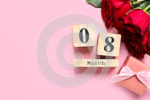 Date 8th of March, roses and gift box on pink background, flat lay with space for text. International Women`s Day