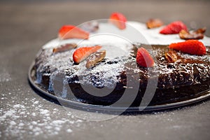 Date cake decorated with sugar, dry dates and fresh strawberries