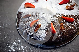Date cake decorated with sugar, dry dates and fresh strawberries