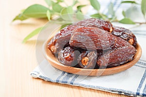 Date fruit in wood bowl on placemat, Dried date palm fruits top view