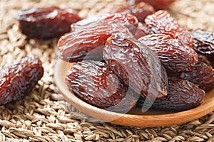 Date fruit in wood bowl on Wicker placemat, Dried date palm fruits top view