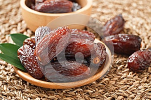 Date fruit in wood bowl on Wicker placemat, Dried date palm fruits top view