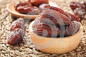 Date fruit in wood bowl on Wicker placemat, Dried date palm fruits top view