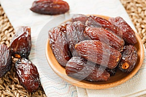 Date fruit in wood bowl on Wicker placemat, Dried date palm fruits top view