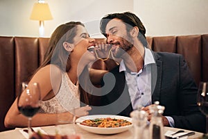Date, laughing and playful couple eating spaghetti on a romantic dinner at a restaurant and enjoying a meal. Lovers, man