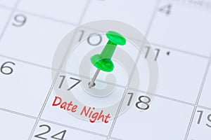 Date Night written on a calendar with a green push pin to remin