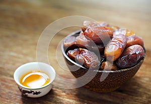 Date-palm in wood bowl with cup of tea on wood