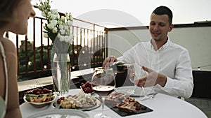 Date on the roof at sunset. Young man is charming his partner. Romantic dinner on the roof