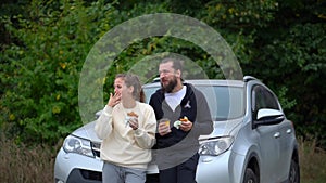 Date of teenagers picnic street. Eat fast food burgers kiss. Laugh at the car and eat a burger. Happy man and woman in
