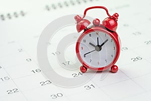 Date and time reminder or deadline concept, small red alarm clock on white clean calendar with number of day, counting down to