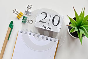 Date on white wooden cubes - the twentieth, 20 April on a white table. Top view