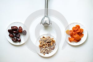 Dates, dried apricots, walnuts, blender on a white background