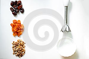 Dates, dried apricots, walnuts, blender on a white background