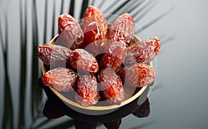 Dates fruit. Date fruits with palm tree leaf reflection on black background. Heap of Medjool dates